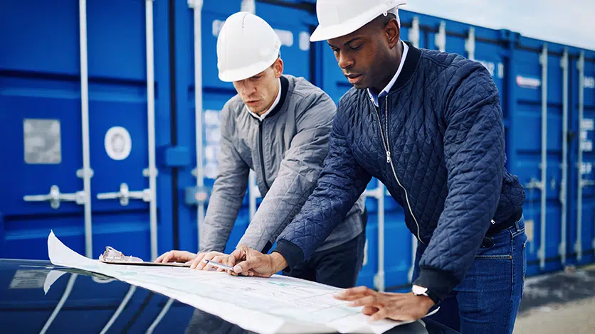 Two men in hard hats examining blueprints for automatic filters and filtration