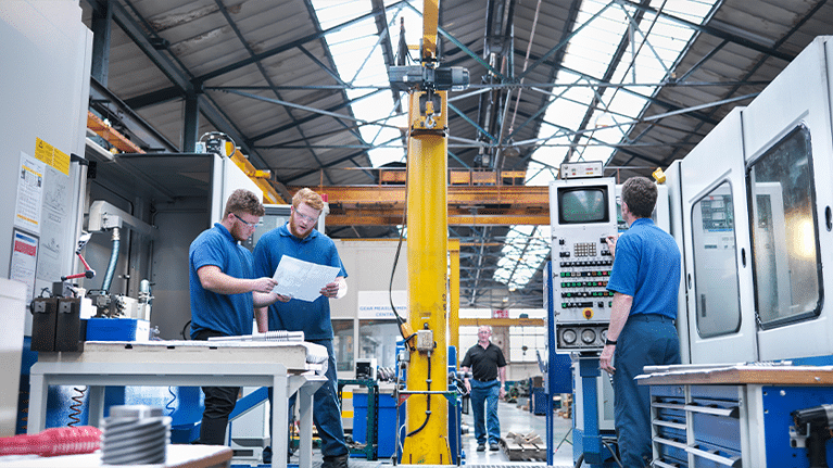 Two men in blue shirts working in a factory, assembling Cabinet Enclosure Coolers